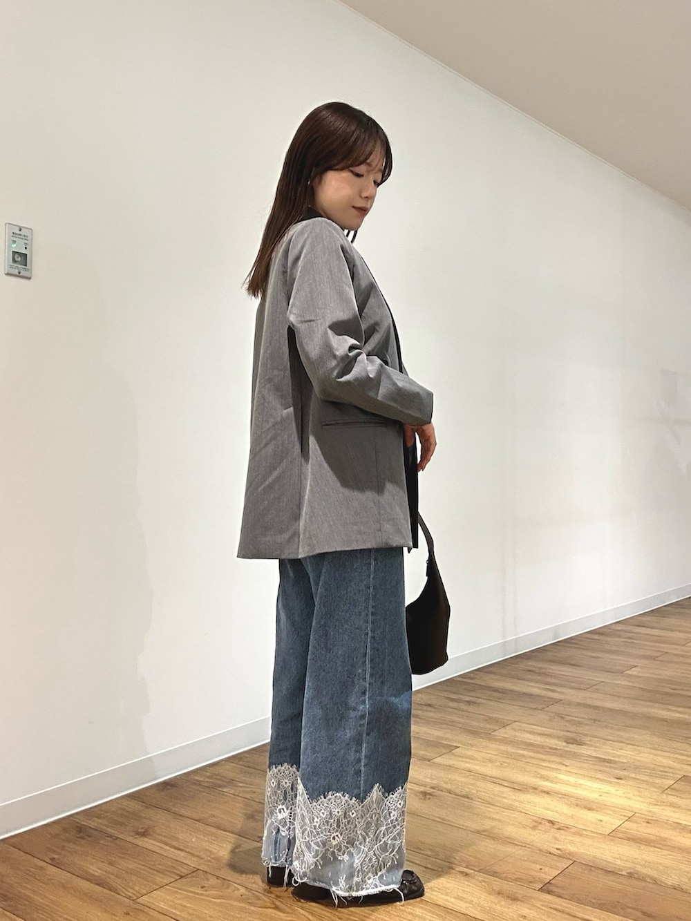 グレー系のテーラードジャケット、ブラック系のニット/セーター、ブルー系のデニムパンツを着用したレディースの春コーディネートの2枚目の写真