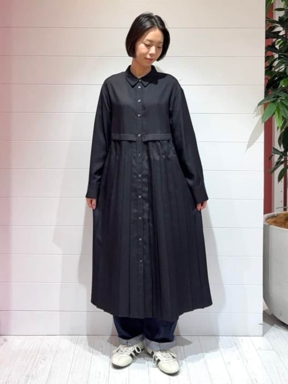 ブルー系のデニムパンツ、ベージュ系のベスト、ブラック系のワンピースを着用したレディースの秋コーディネートの2枚目の写真