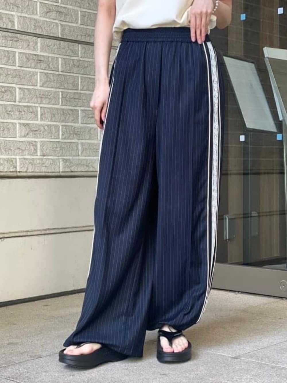 ブルー系のその他パンツ、ブラック系のハンドバッグ、ブラック系のサンダルを着用したレディースの春コーディネートの2枚目の写真