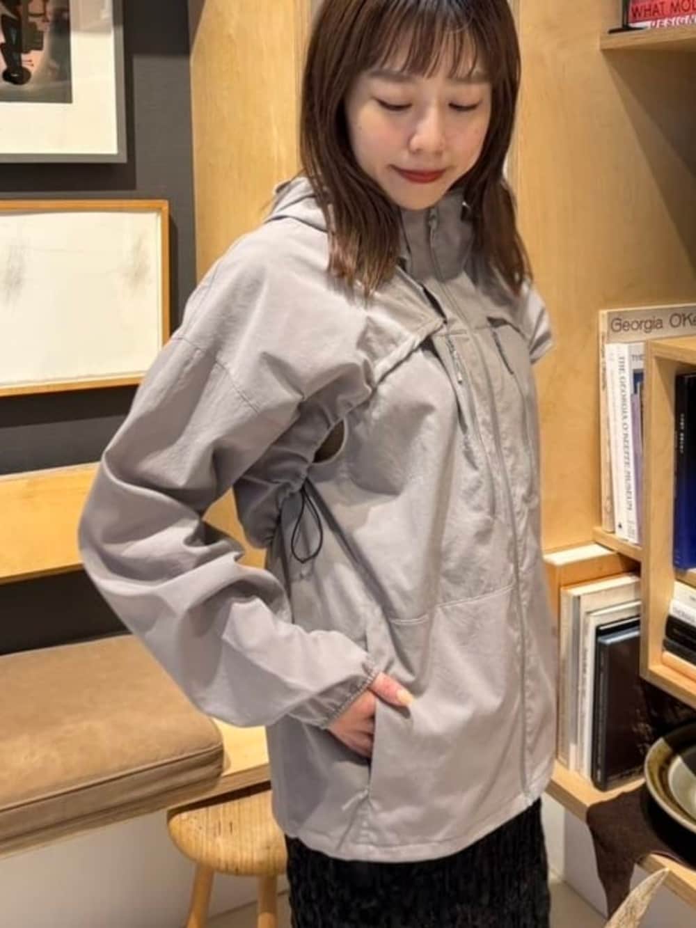 グレー系のナイロンジャケット、ブラウン系のポロシャツ、ブラック系のパンプスを着用したレディースの春コーディネートの2枚目の写真