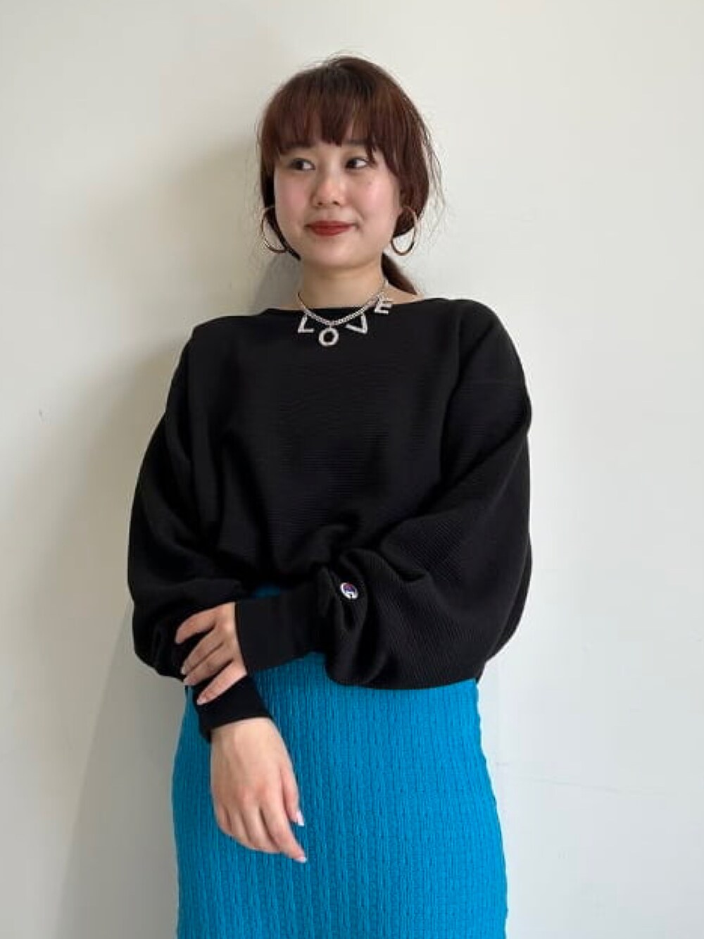 ブルー系のニット/セーター、ブラック系のTシャツ/カットソー、ブルー系のスカートを着用したレディースの冬コーディネートの2枚目の写真