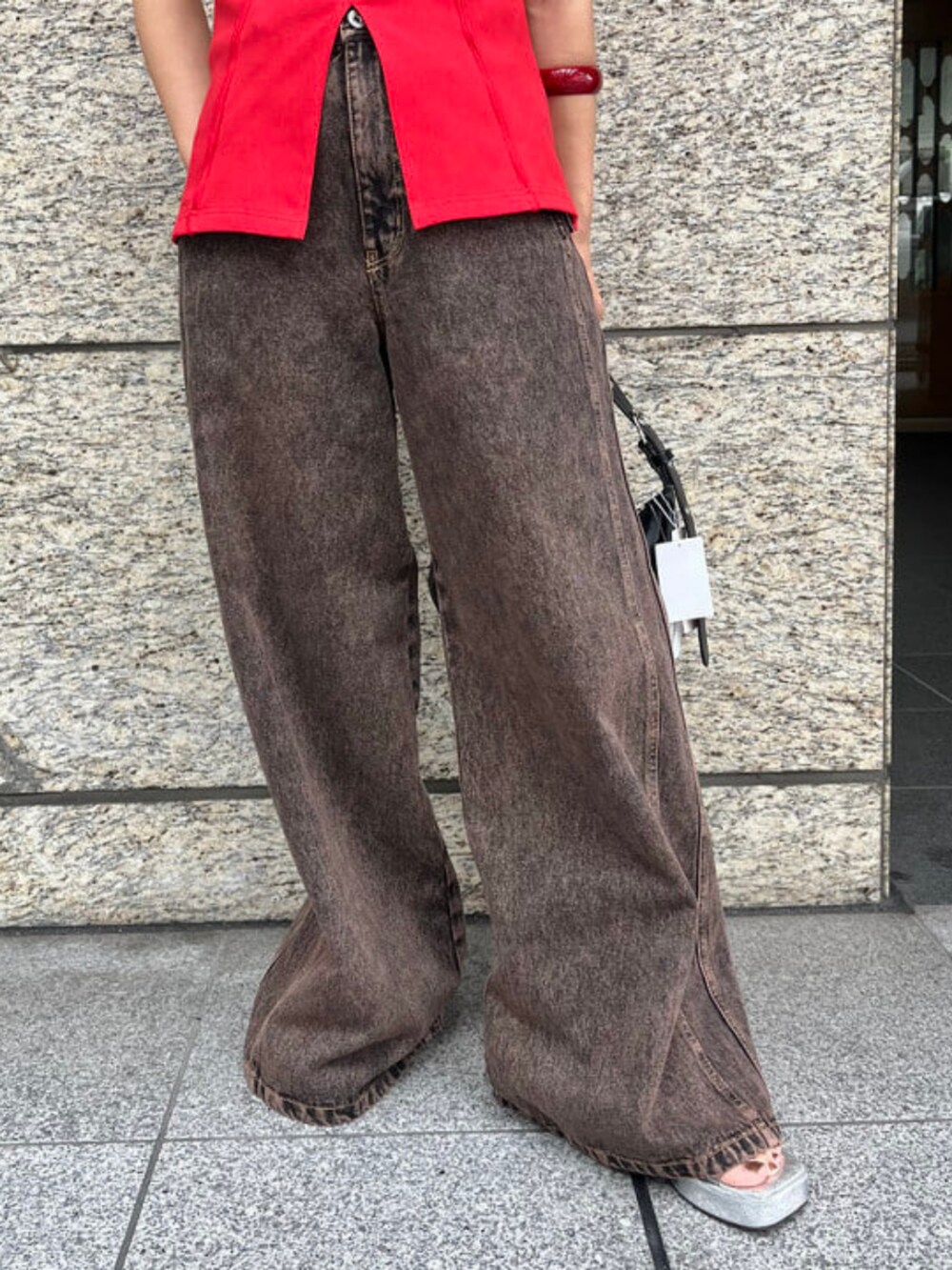 ブラック系のトートバッグ、ブラウン系のデニムパンツ、レッド系のTシャツ/カットソーを着用したレディースの夏コーディネートの3枚目の写真