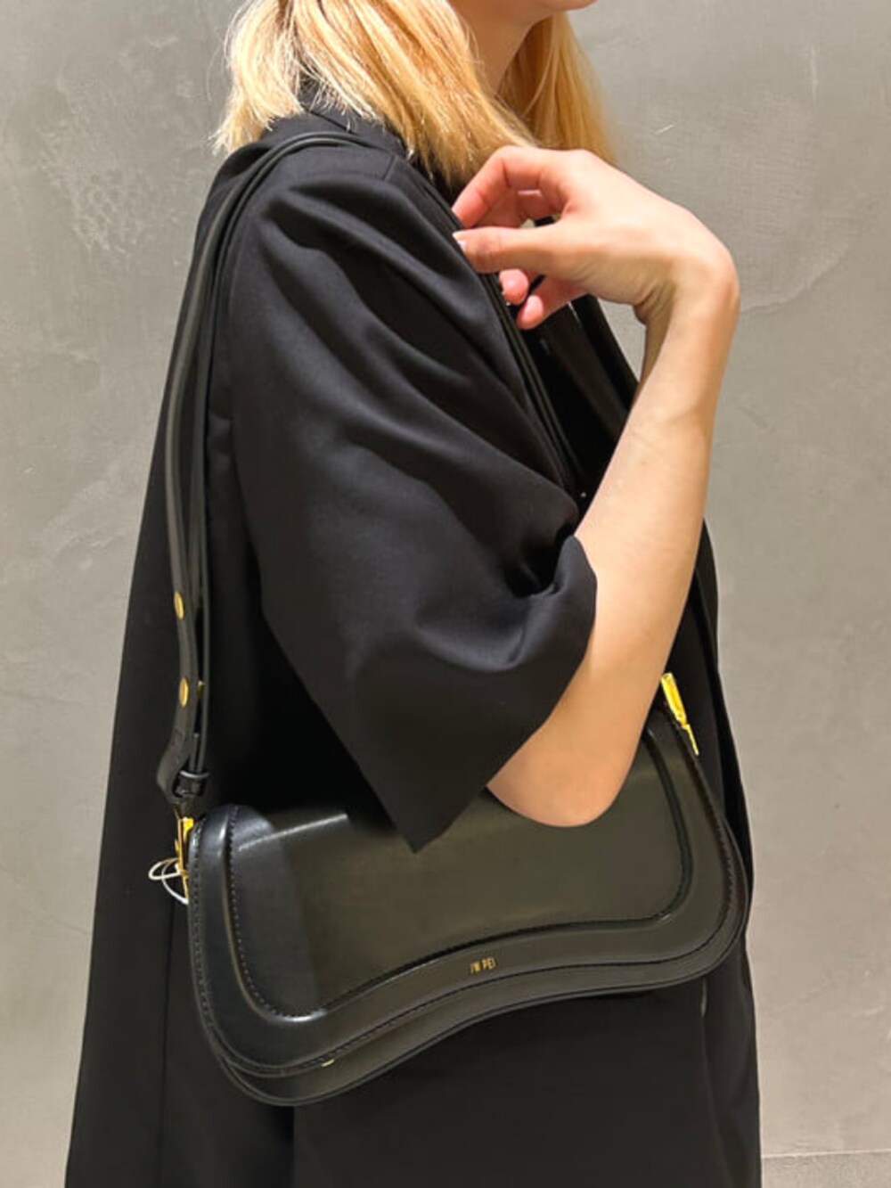 ブラック系のハンドバッグ、ホワイト系のスカート、ブラック系のテーラードジャケットを着用したレディースの春コーディネートの2枚目の写真