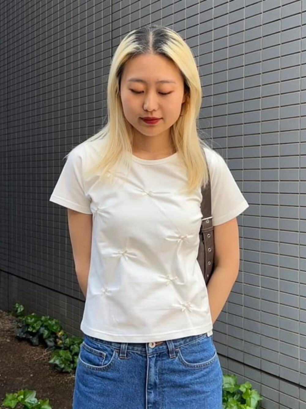 ブラウン系のトートバッグ、ホワイト系のTシャツ/カットソーを着用したレディースの春コーディネートの3枚目の写真