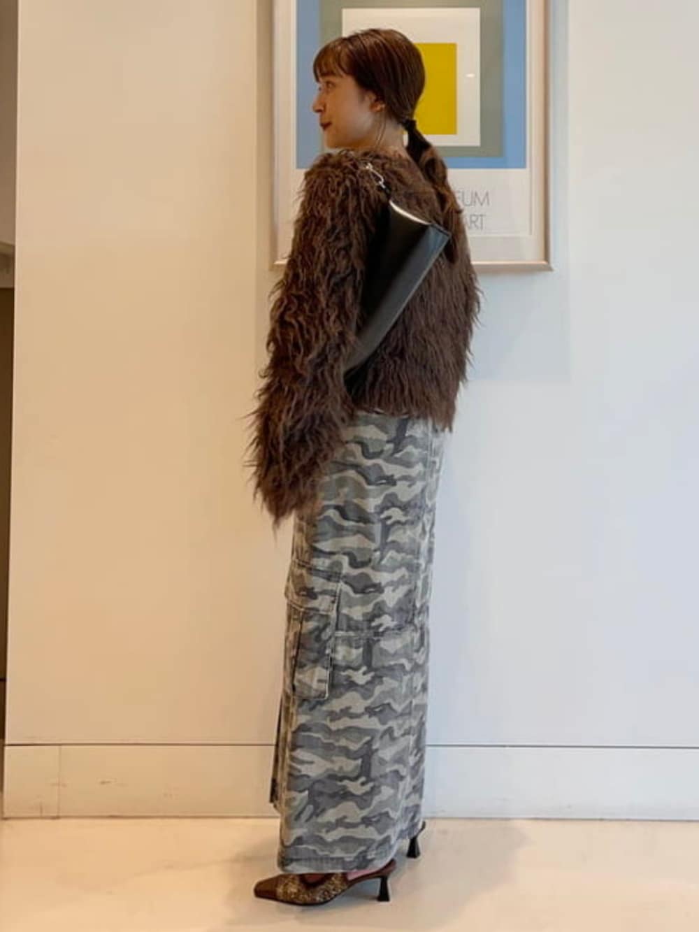 グリーン系のスカート、ブラック系のトートバッグ、ブラウン系のカーディガン/ボレロを着用したレディースの秋コーディネートの2枚目の写真