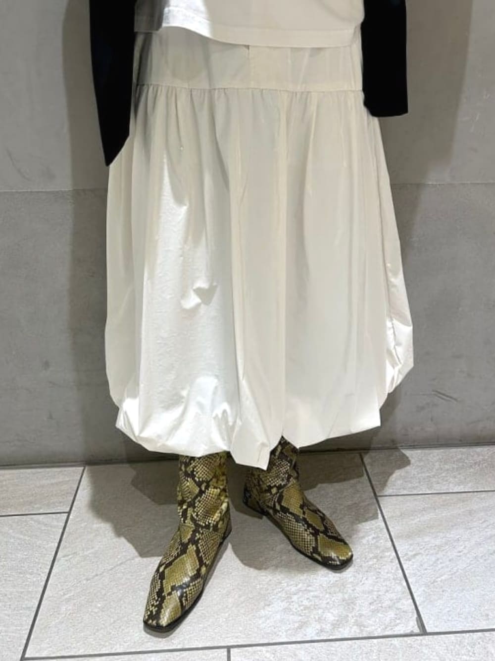 ブラック系のハンドバッグ、ホワイト系のスカート、ブラック系のテーラードジャケットを着用したレディースの春コーディネートの4枚目の写真