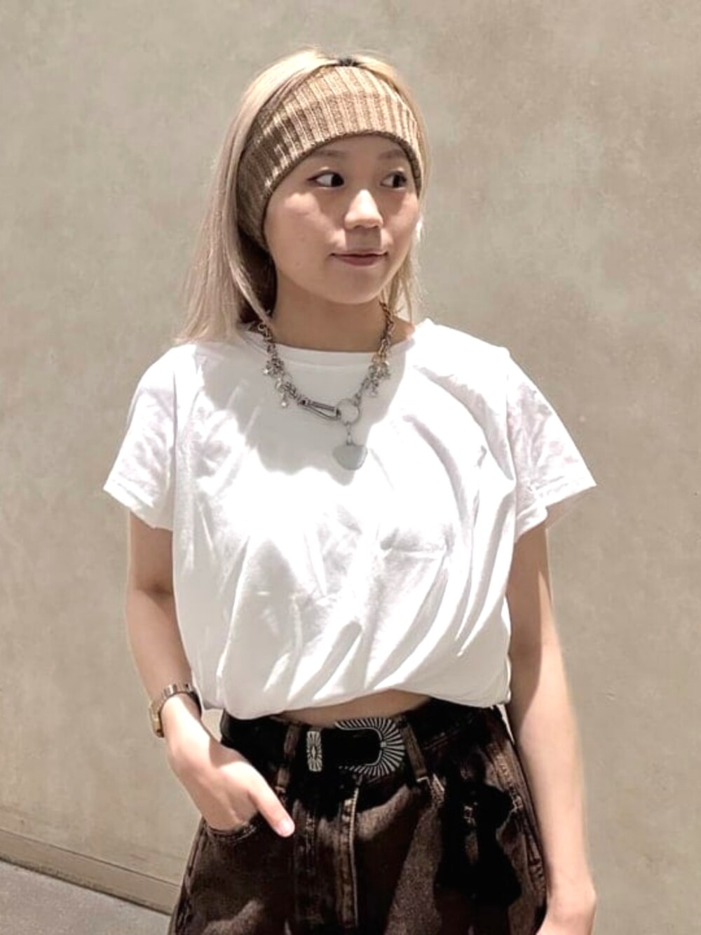 ブラウン系のデニムパンツ、ブラック系のトートバッグ、ホワイト系のTシャツ/カットソーを着用したレディースの夏コーディネートの3枚目の写真