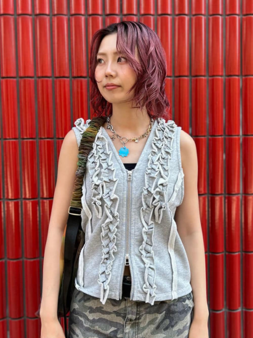 グリーン系のスカート、グレー系のベスト、その他のショルダーバッグを着用したレディースの夏コーディネートの3枚目の写真