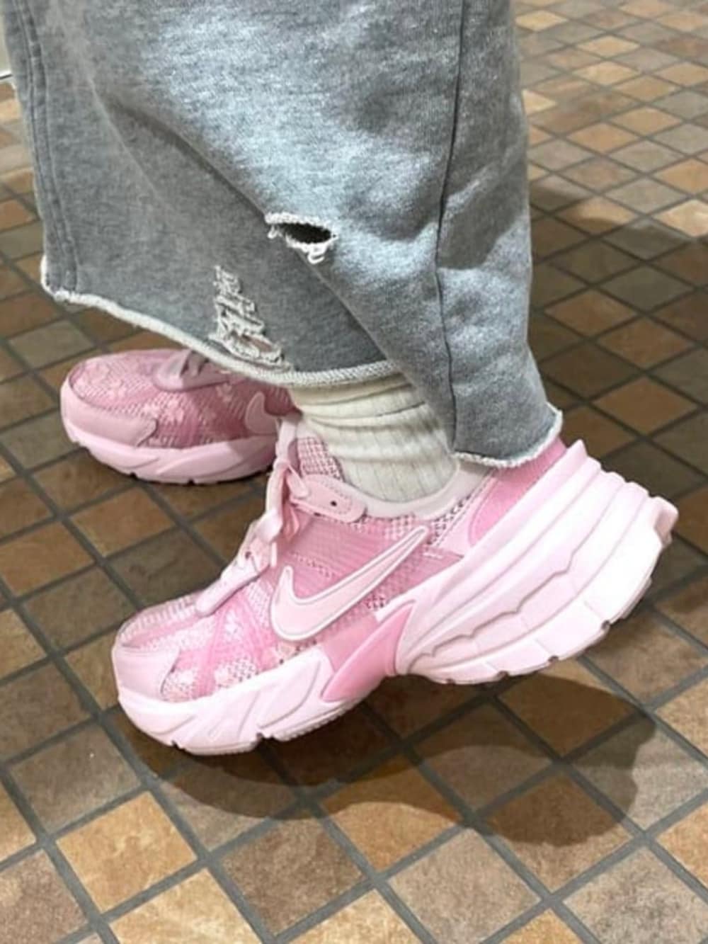 グレー系のスカート、ブラウン系のトートバッグ、ピンク系のスニーカーを着用したレディースの春コーディネートの2枚目の写真