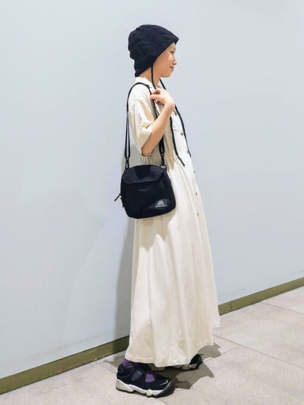 ホワイト系のワンピース、ブラック系のショルダーバッグ、ブラック系のハットを着用したレディースの春コーディネートの2枚目の写真