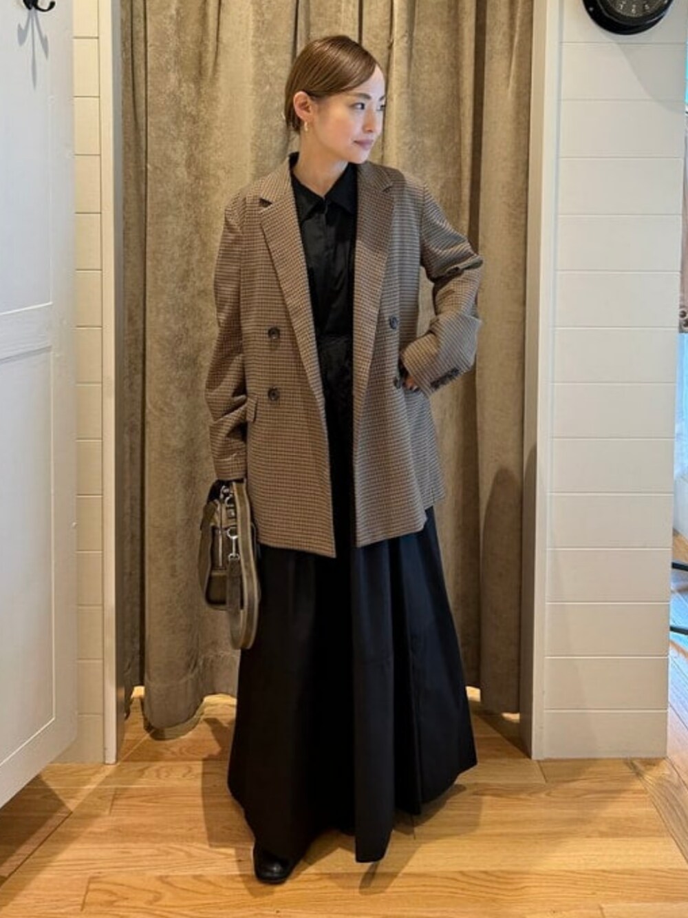 ブラウン系のテーラードジャケット、ブラウン系のハンドバッグ、ブラック系のワンピースを着用したレディースの春コーディネートの2枚目の写真