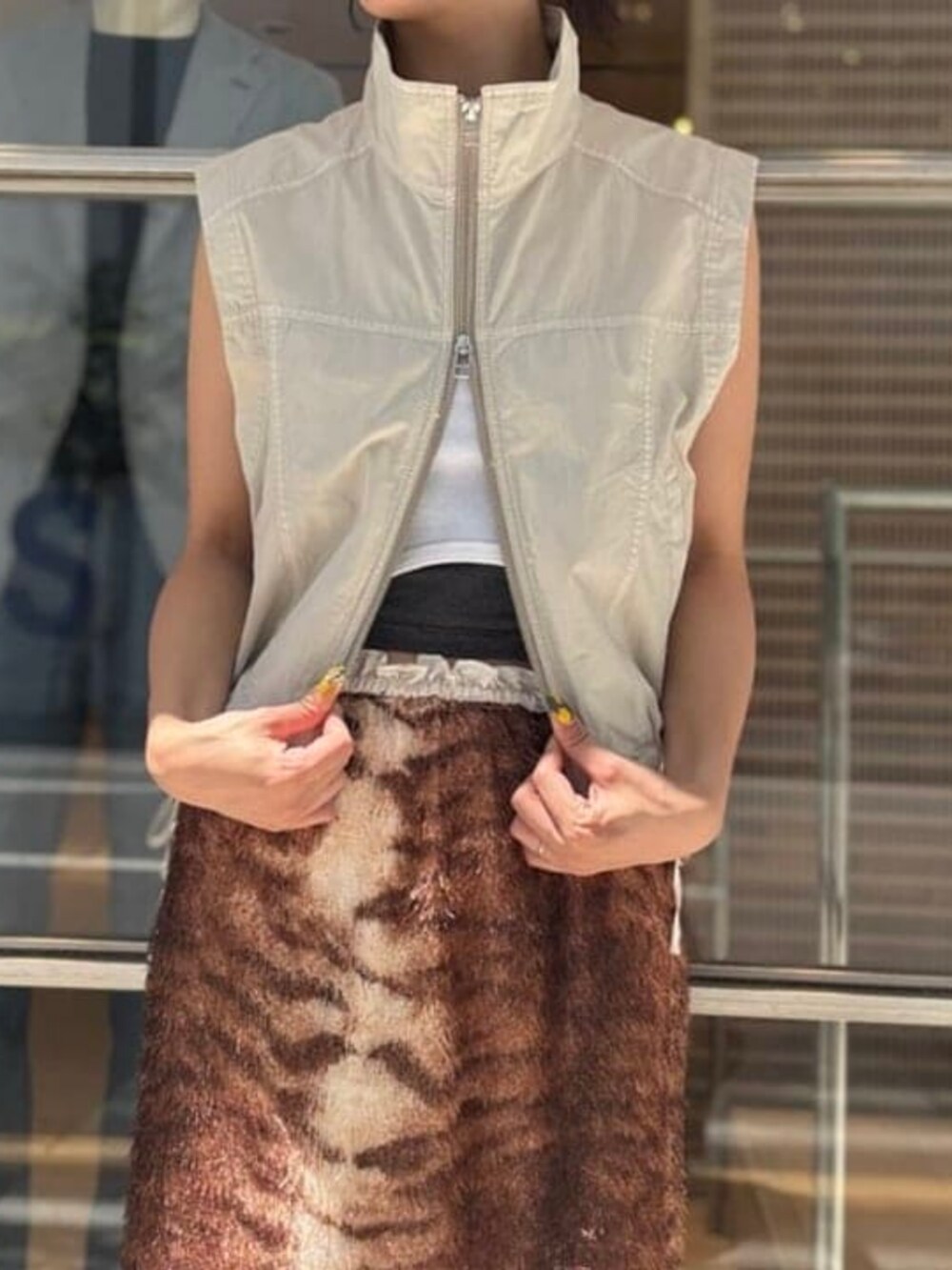 ブラウン系のスカート、ベージュ系のベストを着用したレディースの夏コーディネートの2枚目の写真