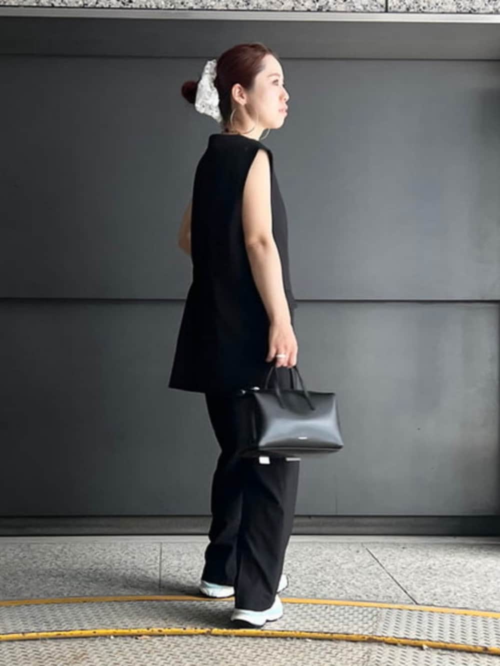 ブラック系のベスト、ブラック系のスラックス、ブラック系のトートバッグを着用したレディースの夏コーディネートの2枚目の写真