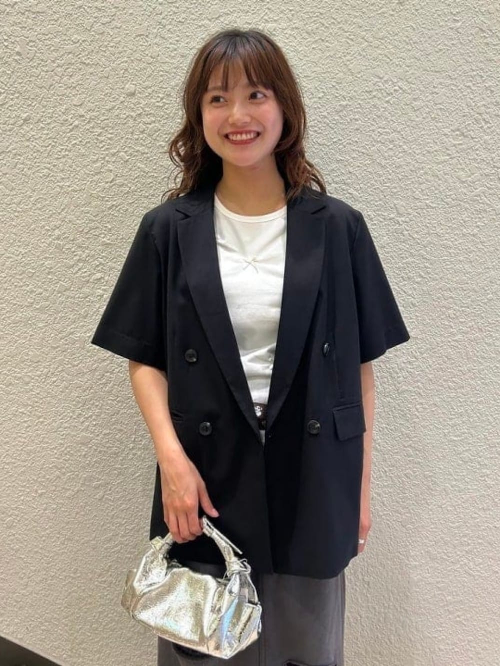 グレー系のスカート、ブラック系のテーラードジャケット、ホワイト系のTシャツ/カットソーを着用したレディースの春コーディネートの2枚目の写真