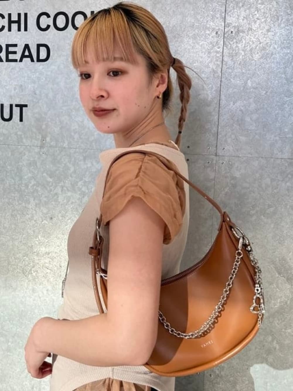 ブラウン系のトートバッグ、ブルー系のスラックス、ブラウン系のTシャツ/カットソーを着用したレディースの春コーディネートの3枚目の写真