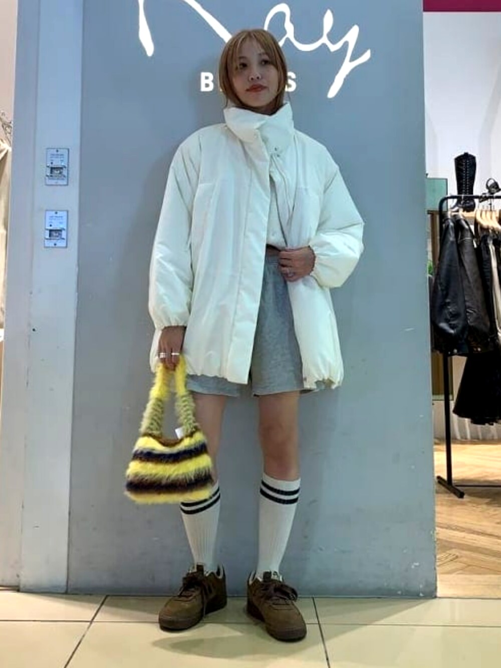 イエロー系のトートバッグ、ホワイト系のブルゾンを着用したレディースの秋コーディネートの2枚目の写真