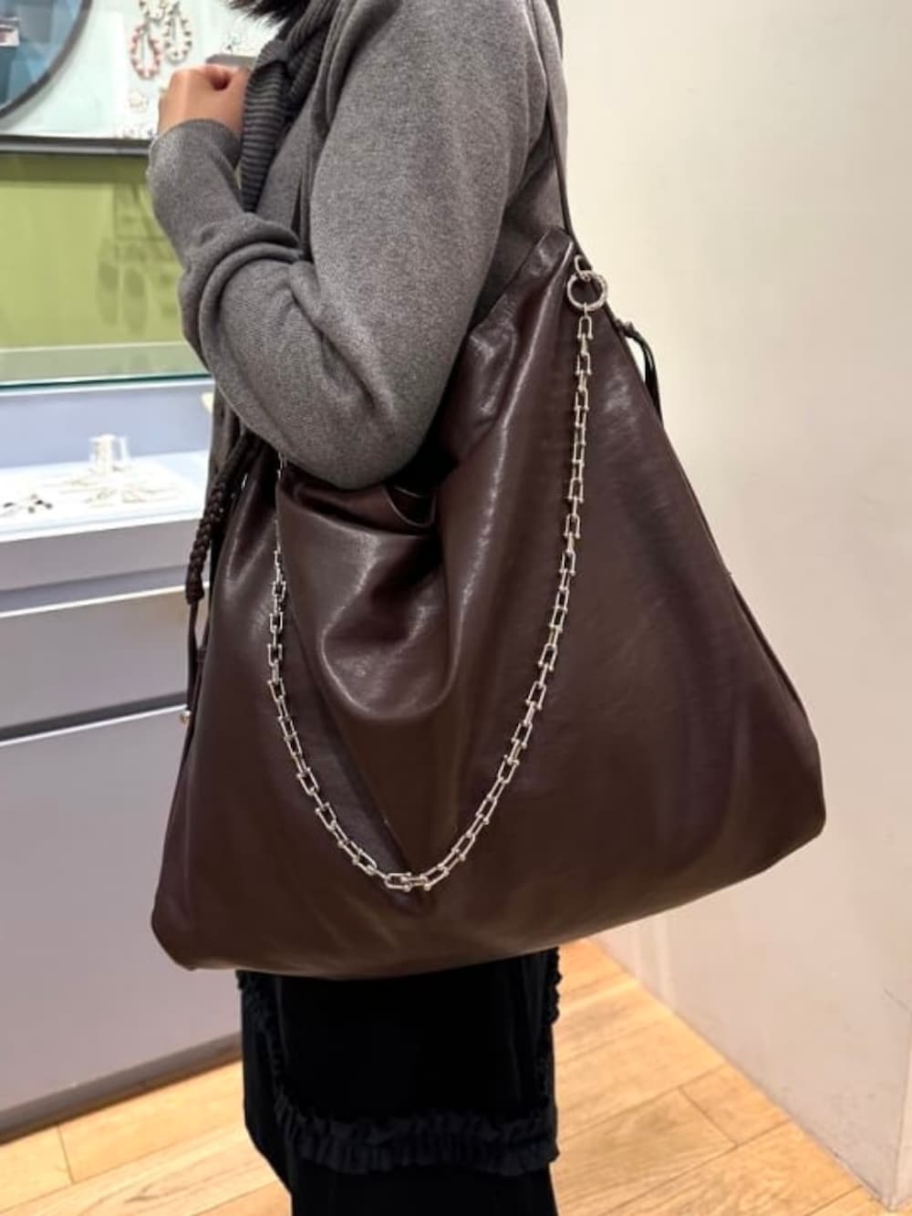ブラウン系のトートバッグ、シルバー系のニット/セーター、ブラック系のスカートを着用したレディースの秋コーディネートの2枚目の写真