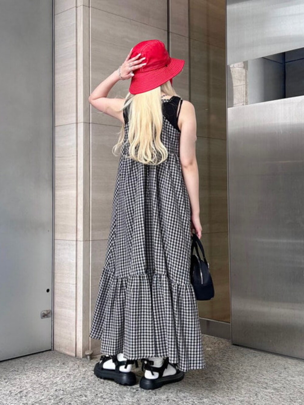 ブラック系のボストンバッグ、ブラック系のワンピース、レッド系のハットを着用したレディースの春コーディネートの2枚目の写真