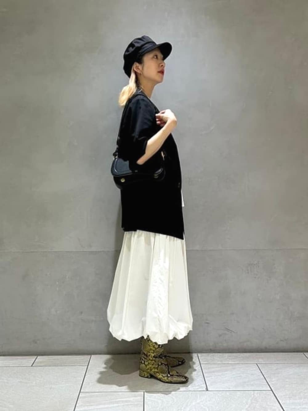 ブラック系のハンドバッグ、ホワイト系のスカート、ブラック系のテーラードジャケットを着用したレディースの春コーディネートの5枚目の写真