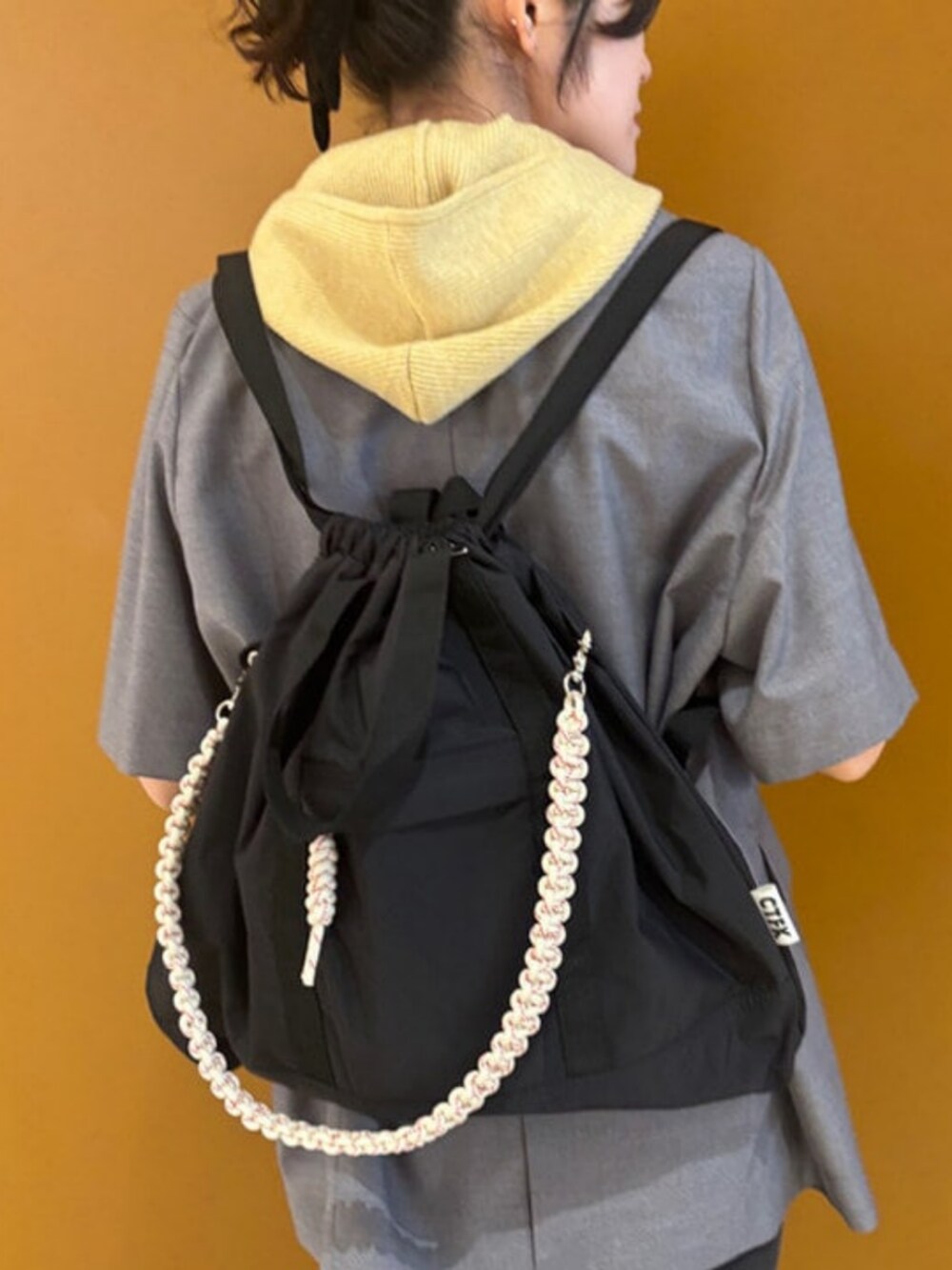 グレー系のテーラードジャケット、ブラック系のトートバッグ、ベージュ系のベストを着用したレディースの春コーディネートの2枚目の写真