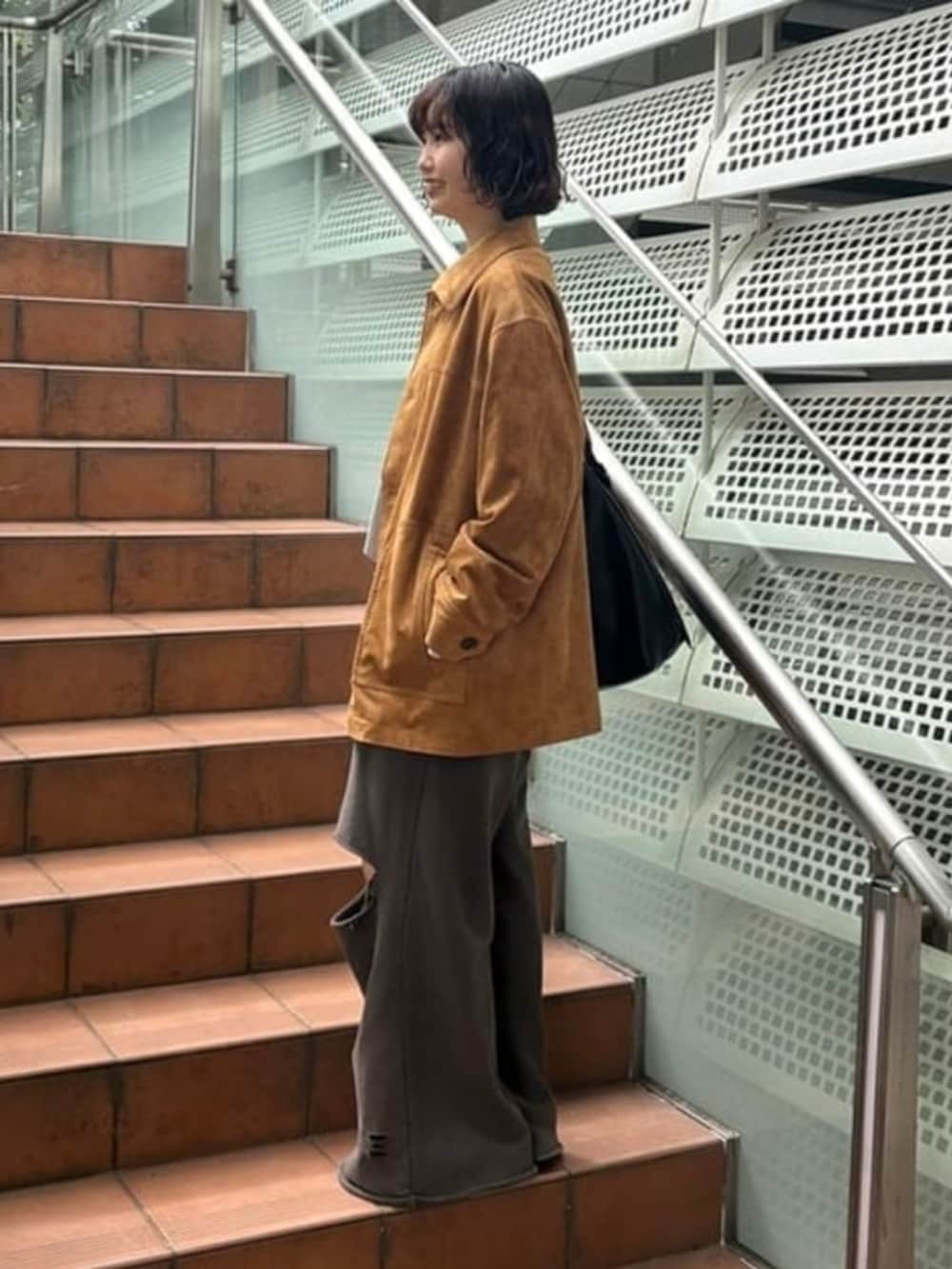 ブラック系のショルダーバッグ、グレー系のスウェットパンツ、グリーン系のその他アウターを着用したレディースの秋コーディネートの2枚目の写真