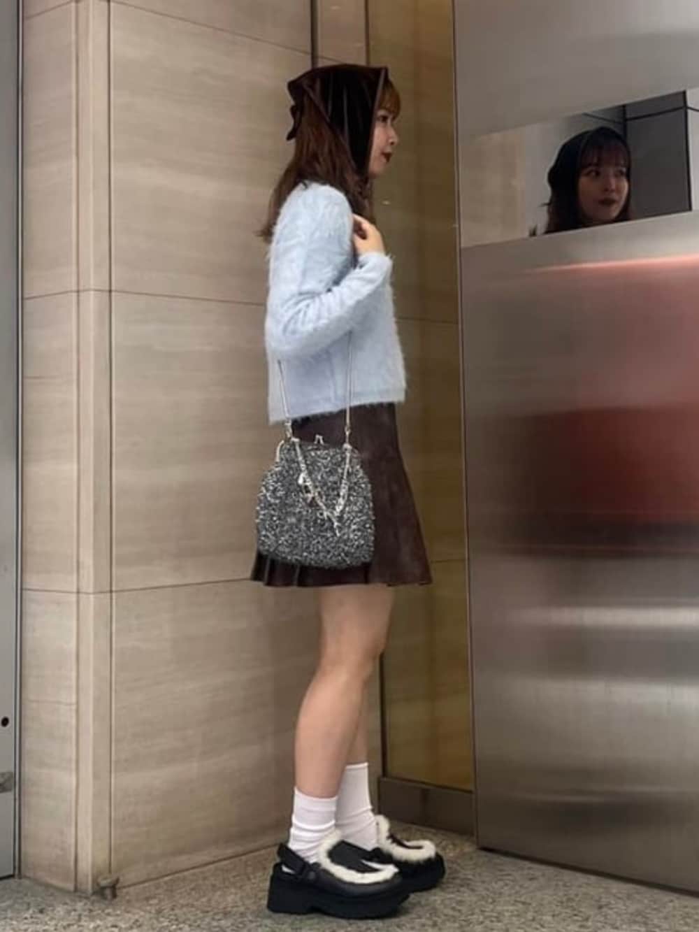 ブルー系のカーディガン/ボレロ、ブラウン系のスカート、ブラック系のトートバッグを着用したレディースの秋コーディネートの2枚目の写真