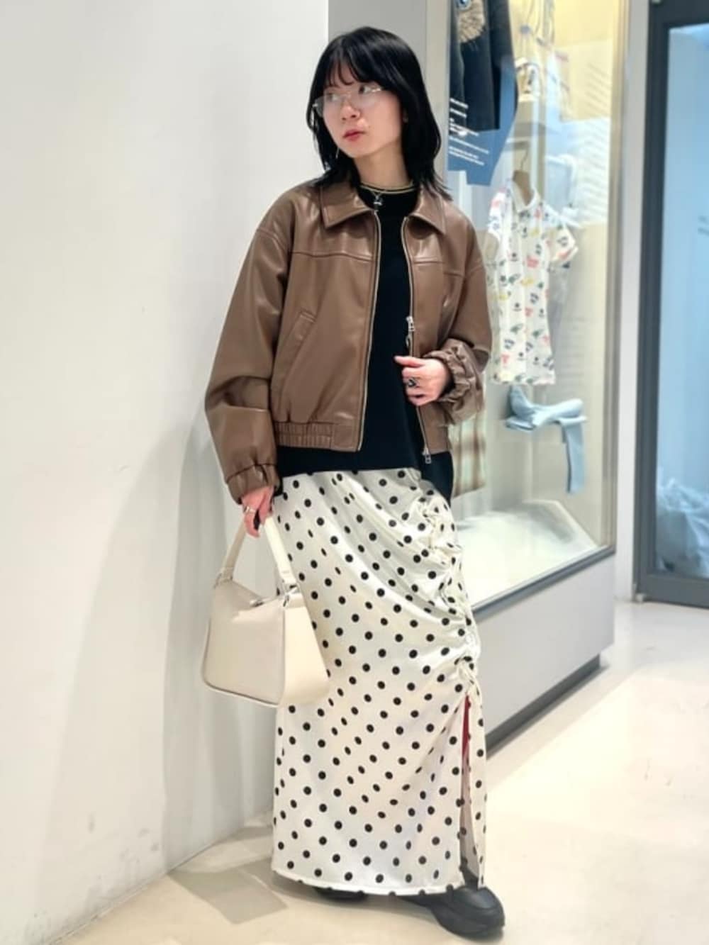 ブラック系のTシャツ/カットソー、ホワイト系のスカート、ブラウン系のブルゾンを着用したレディースの春コーディネートの2枚目の写真