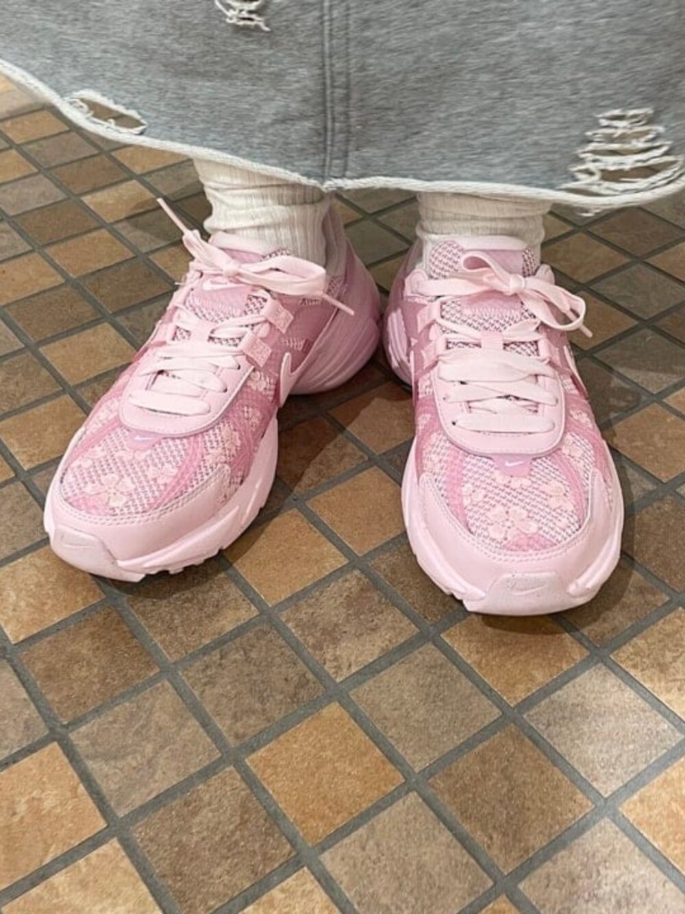 グレー系のスカート、ブラウン系のトートバッグ、ピンク系のスニーカーを着用したレディースの春コーディネートの3枚目の写真