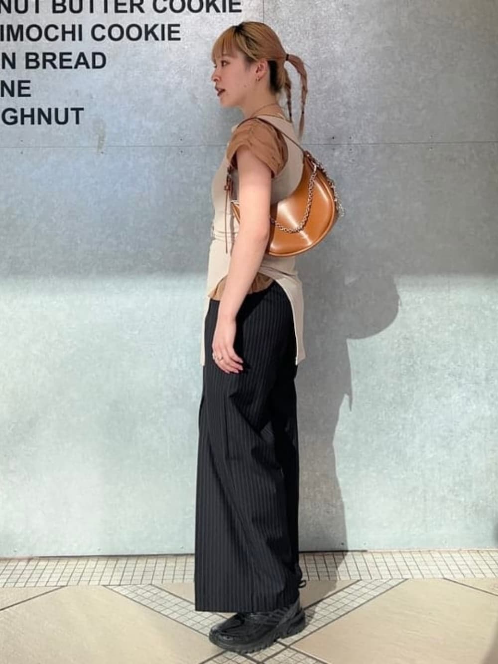 ブラウン系のトートバッグ、ブルー系のスラックス、ブラウン系のTシャツ/カットソーを着用したレディースの春コーディネートの2枚目の写真