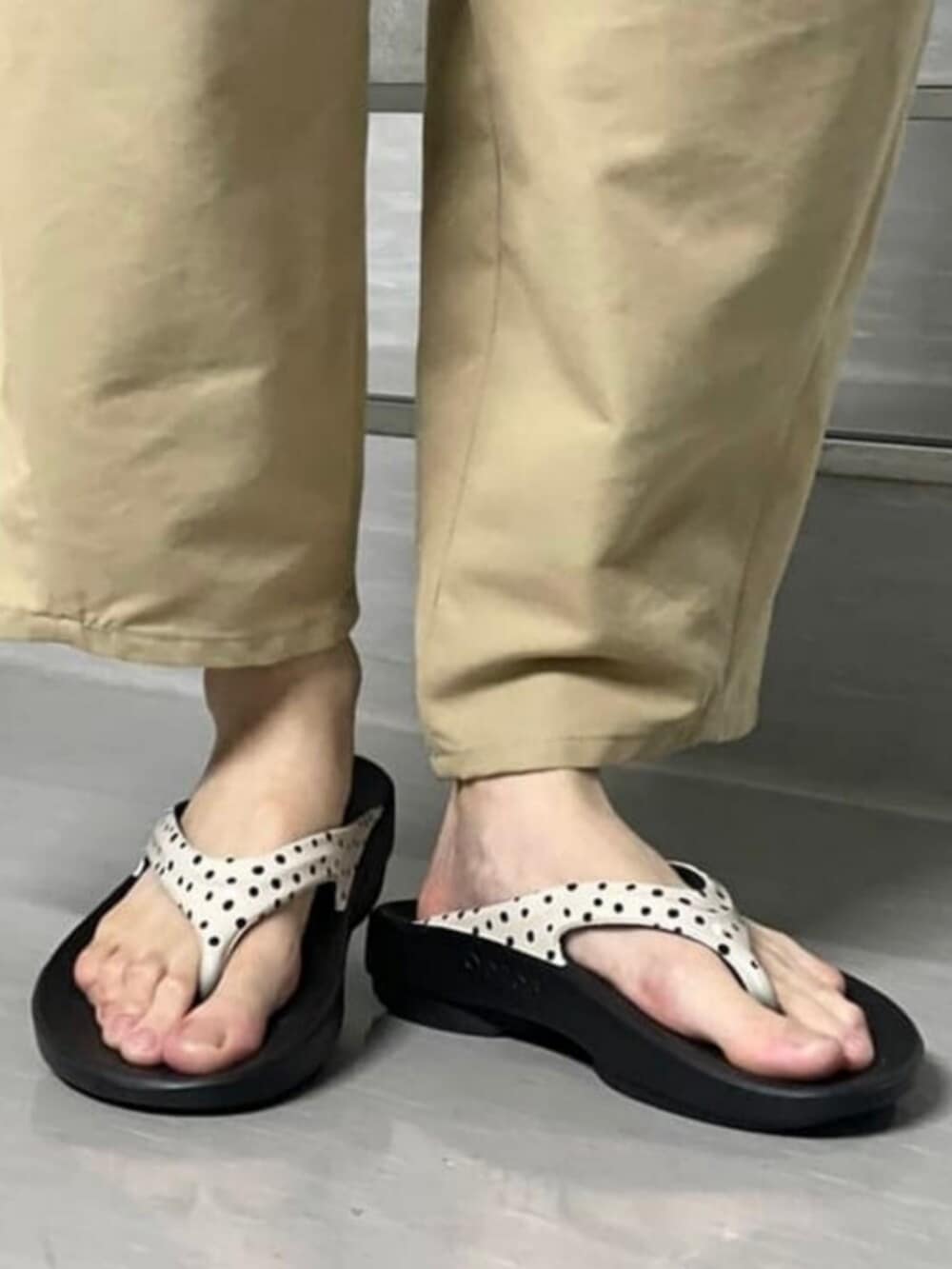 ブラック系のトートバッグ、ブラウン系のポロシャツ、グリーン系のチノパンツを着用したレディースの夏コーディネートの2枚目の写真
