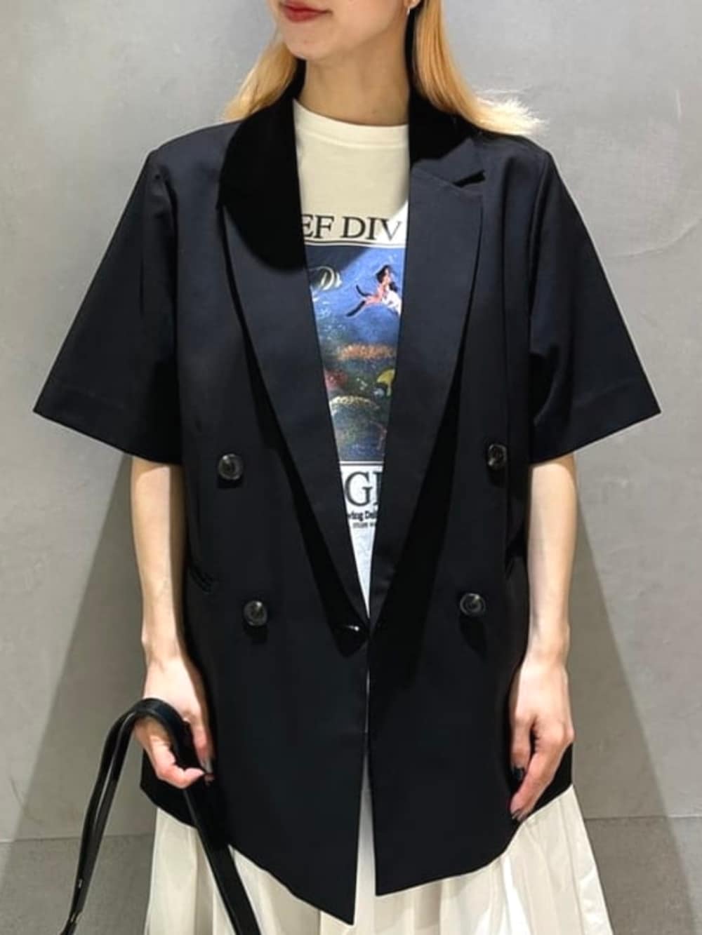 ブラック系のハンドバッグ、ホワイト系のスカート、ブラック系のテーラードジャケットを着用したレディースの春コーディネートの3枚目の写真