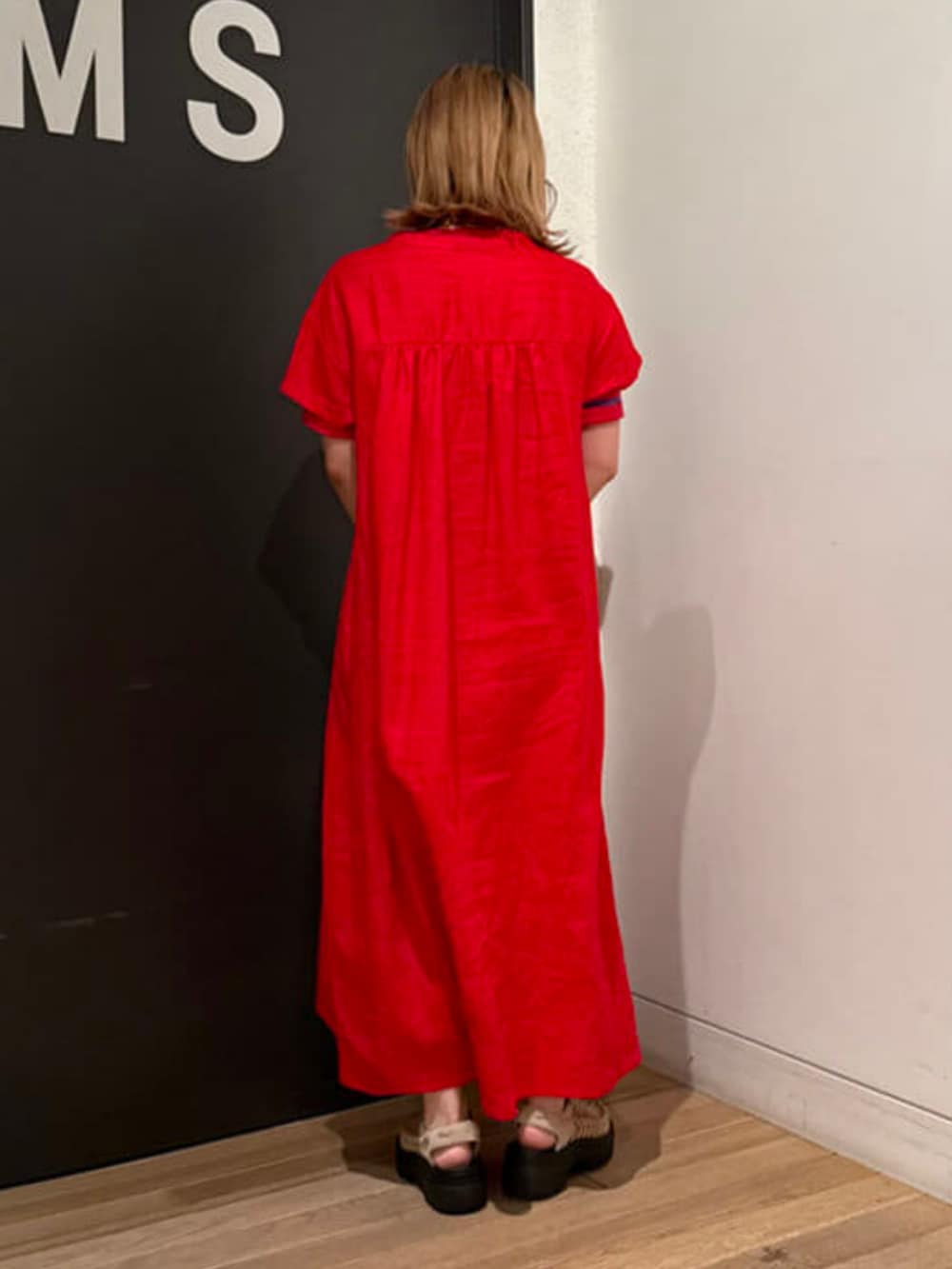 レッド系のワンピース、ブラウン系のかごバッグ、ベージュ系のサンダルを着用したレディースの春コーディネートの2枚目の写真