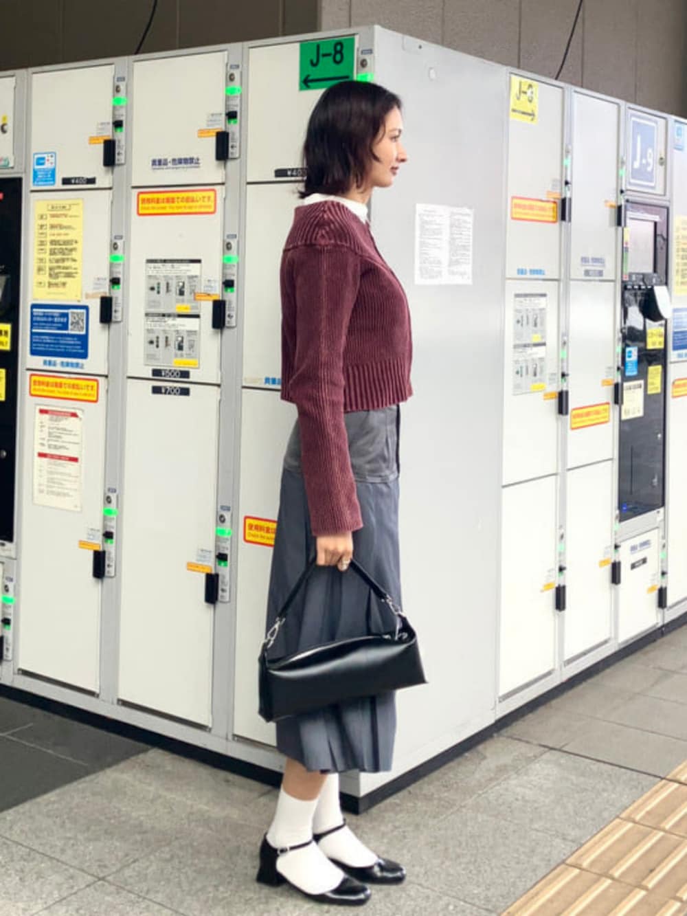 ブラック系のトートバッグ、レッド系のカーディガン/ボレロ、シルバー系のスカートを着用したレディースの冬コーディネートの2枚目の写真