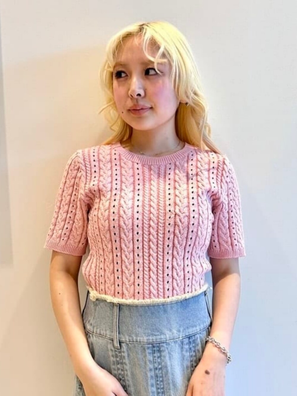 ピンク系のショルダーバッグ、ブルー系のデニムスカート、ピンク系のニット/セーターを着用したレディースの春コーディネートの3枚目の写真