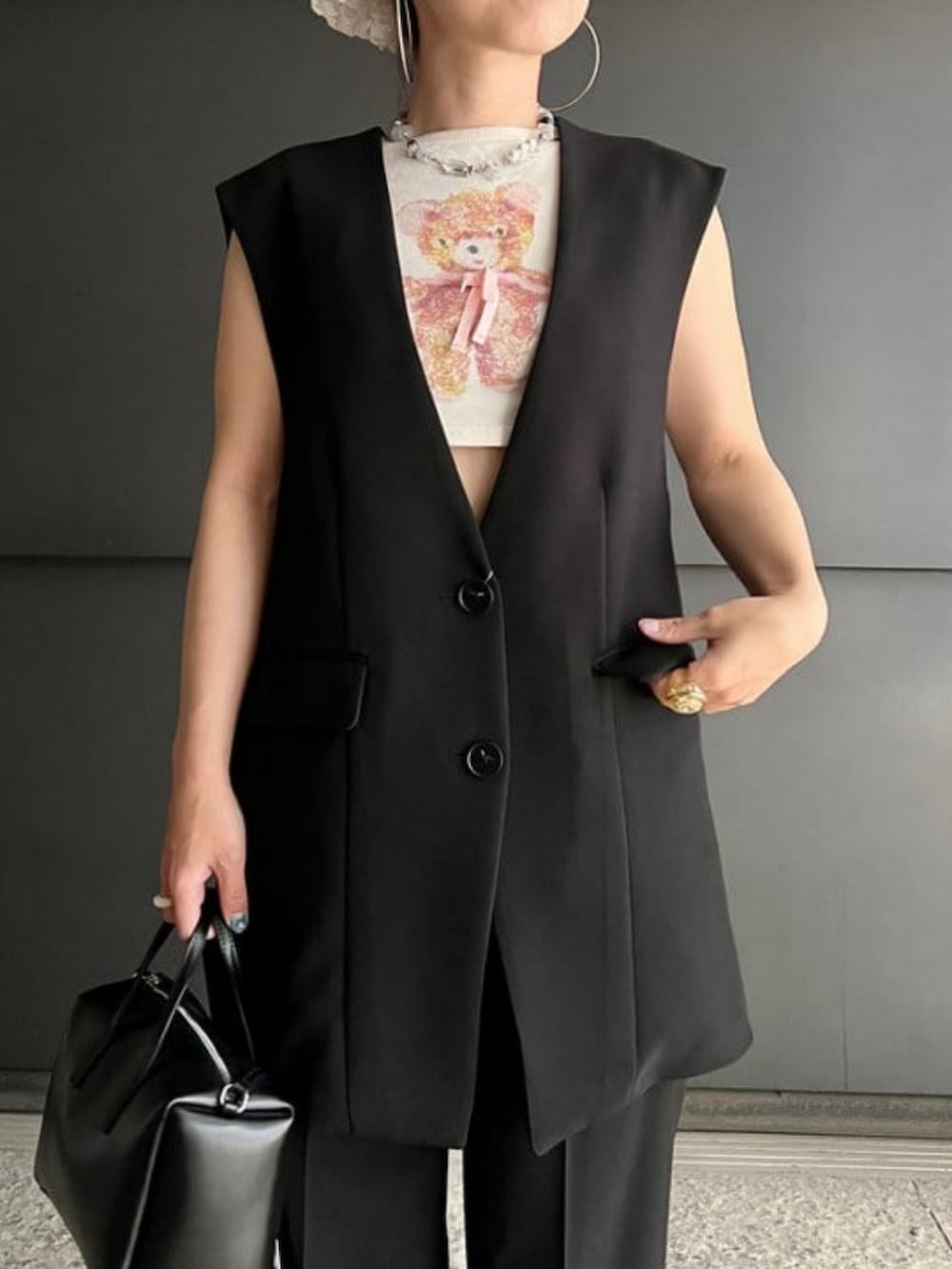 ブラック系のベスト、ブラック系のスラックス、ブラック系のトートバッグを着用したレディースの夏コーディネートの3枚目の写真