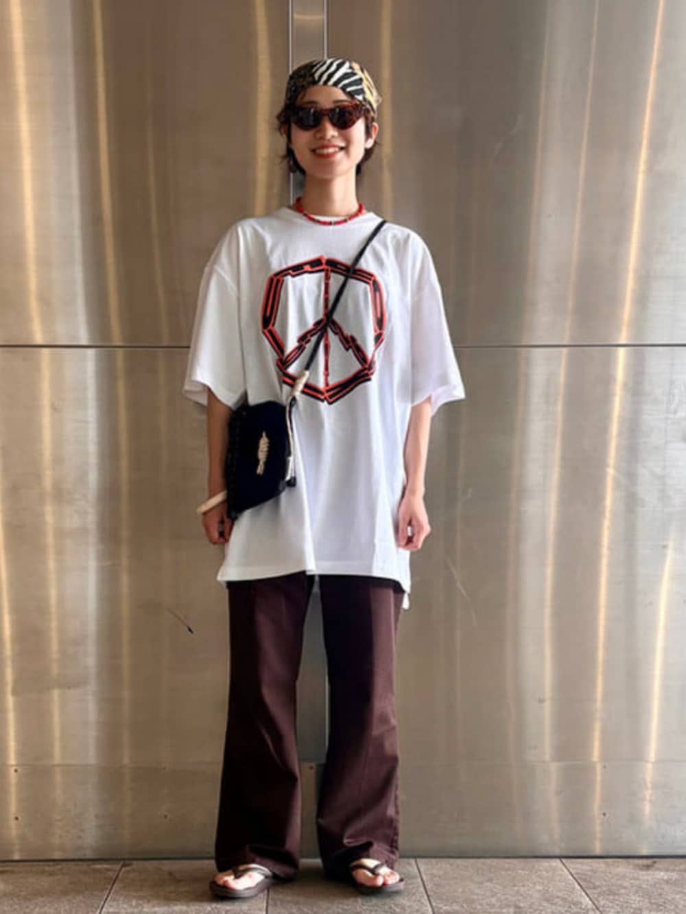 ブラック系のショルダーバッグ、ホワイト系のTシャツ/カットソーを着用したレディースの夏コーディネートの2枚目の写真