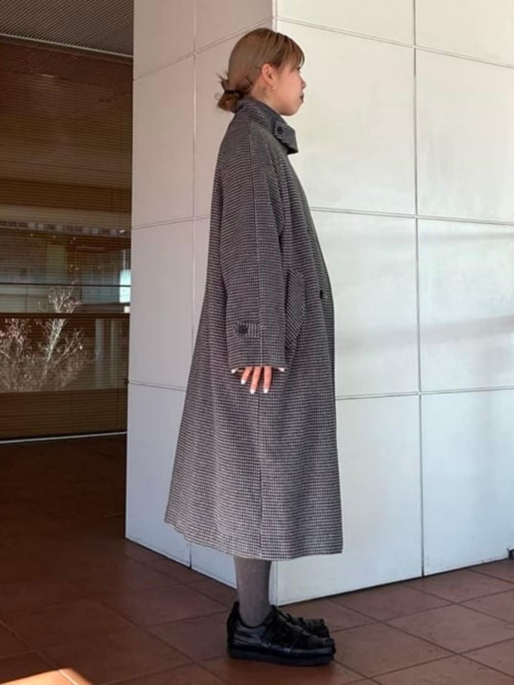 シルバー系のステンカラーコート、ブラック系のスカートを着用したレディースの秋コーディネートの2枚目の写真