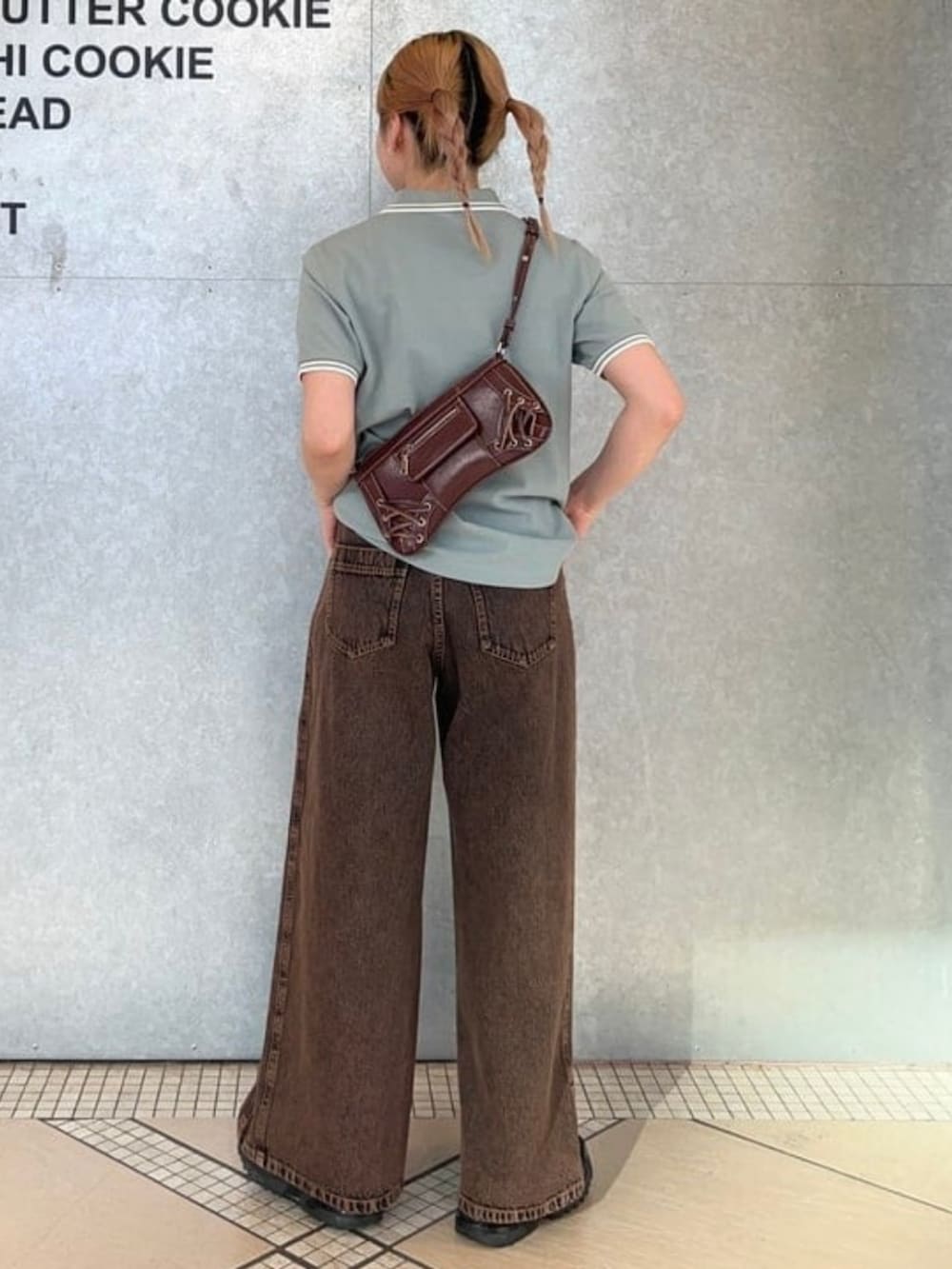 ブラウン系のショルダーバッグ、ブラウン系のデニムパンツ、ブルー系のポロシャツを着用したレディースの春コーディネートの2枚目の写真