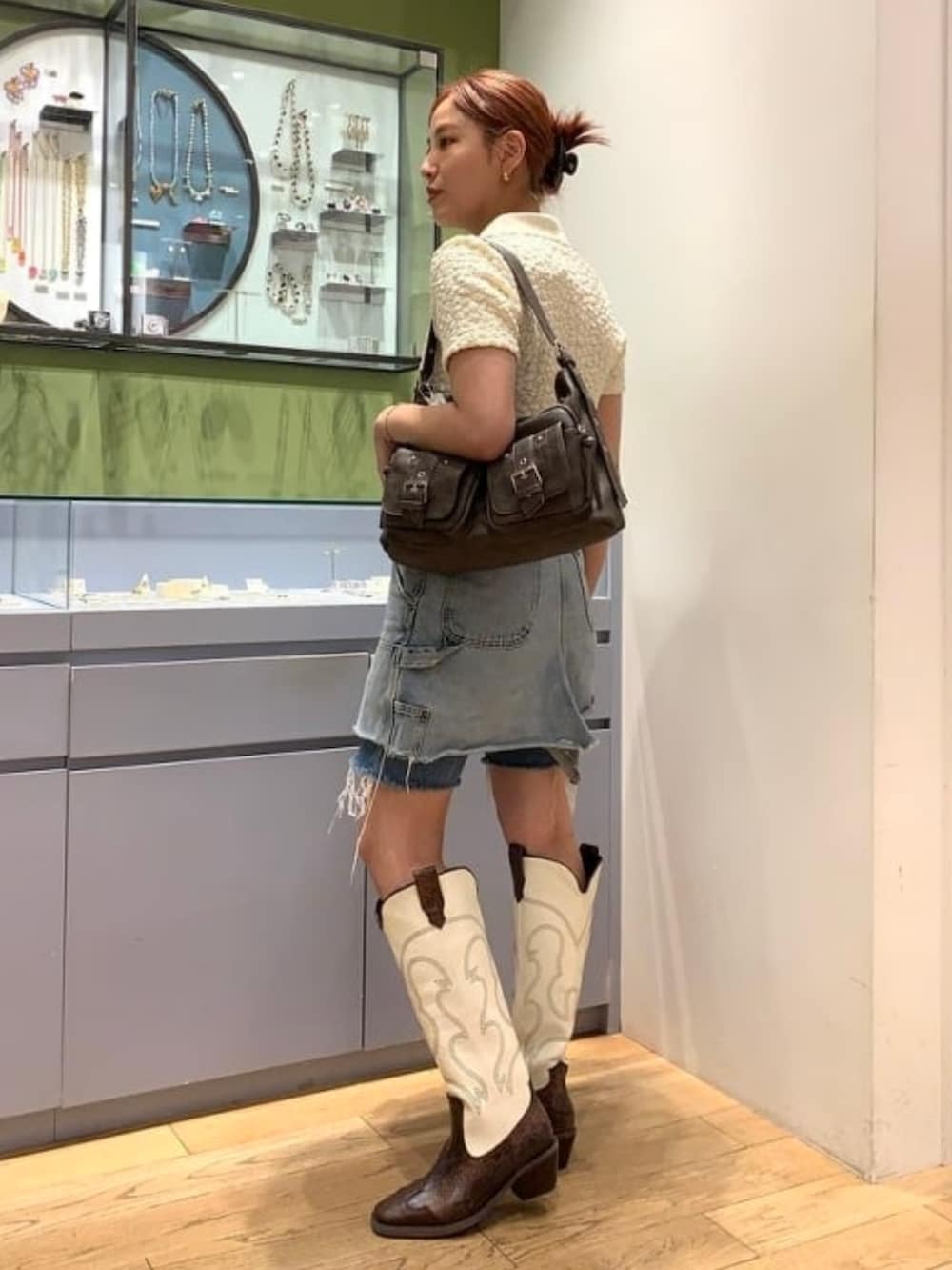 ブラウン系のトートバッグ、ホワイト系のTシャツ/カットソー、ブラウン系のブーツを着用したレディースの春コーディネートの2枚目の写真