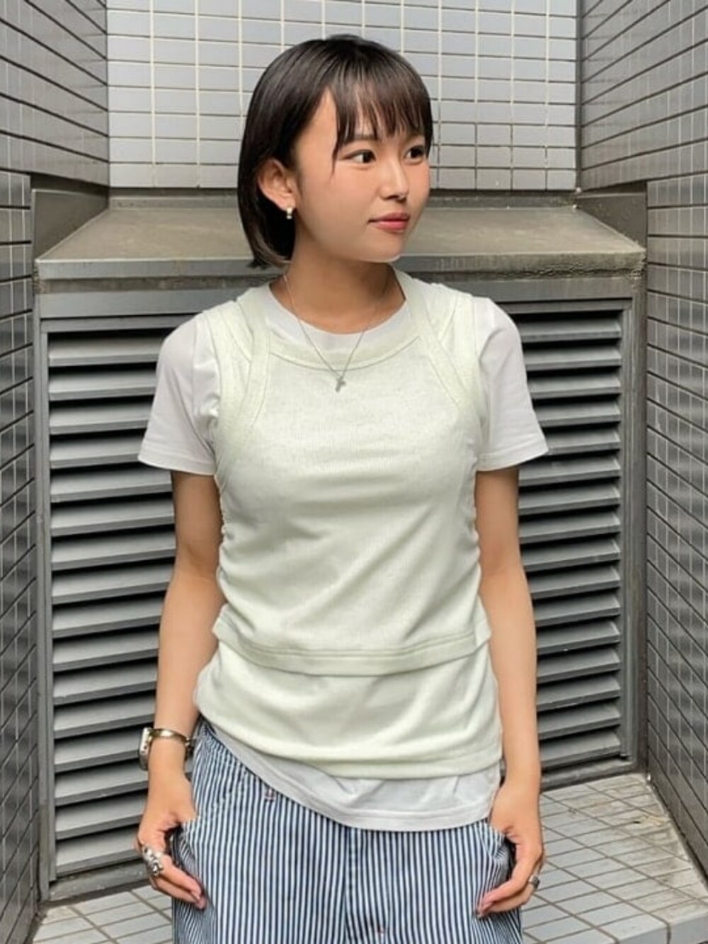 グリーン系のタンクトップ、ホワイト系のTシャツ/カットソーを着用したレディースの夏コーディネートの2枚目の写真