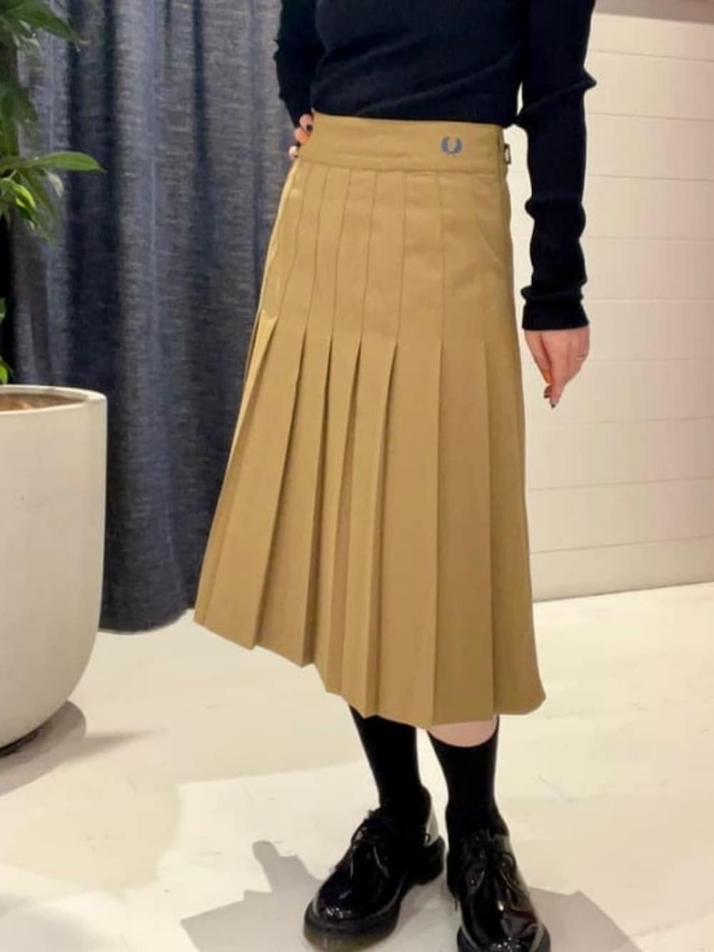 レッド系のトートバッグ、グリーン系のスカート、ブルー系のポロシャツを着用したレディースの秋コーディネートの2枚目の写真