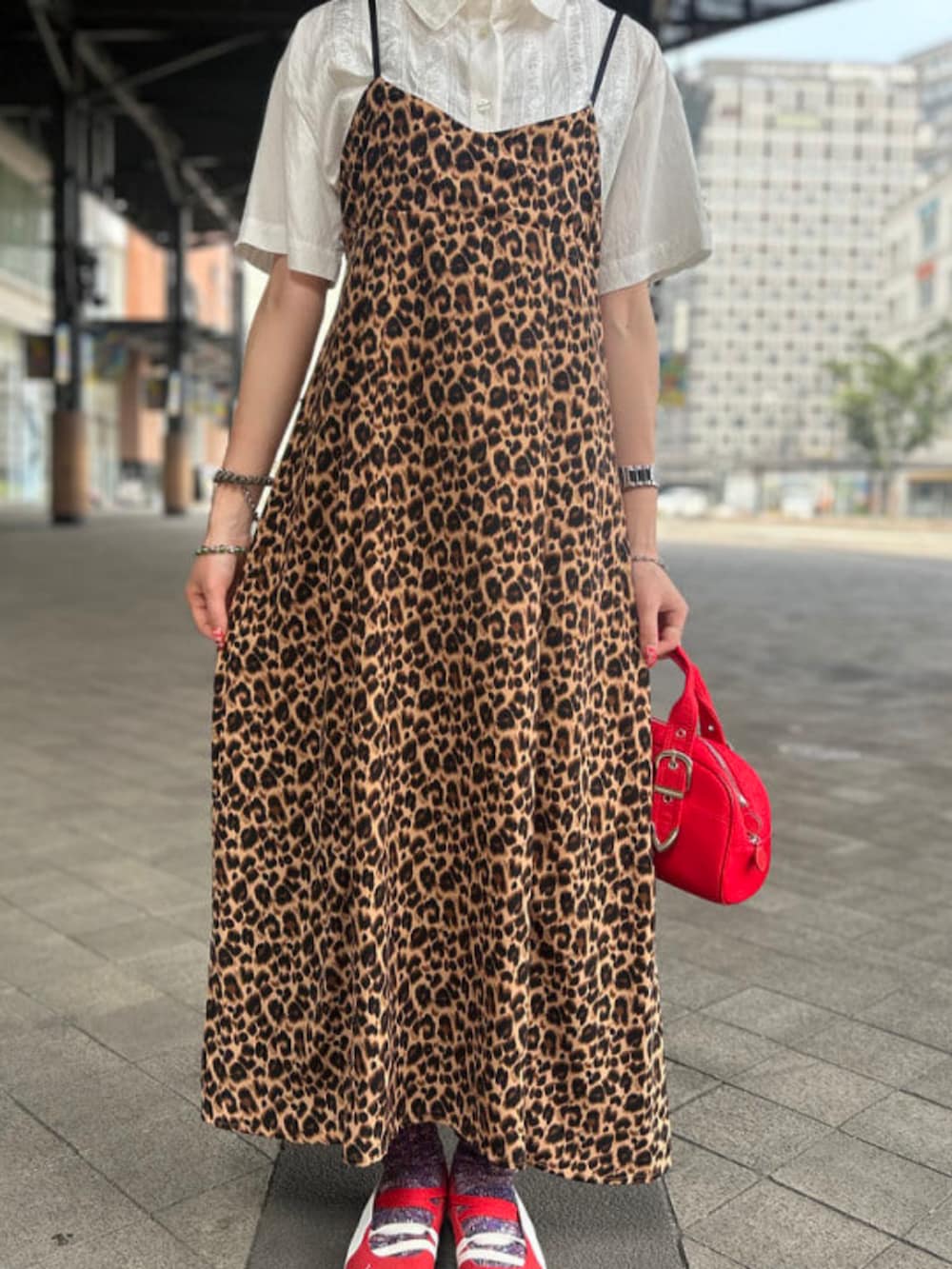 レッド系のボストンバッグ、ホワイト系のシャツ/ブラウス、レッド系のスニーカーを着用したレディースの夏コーディネートの2枚目の写真