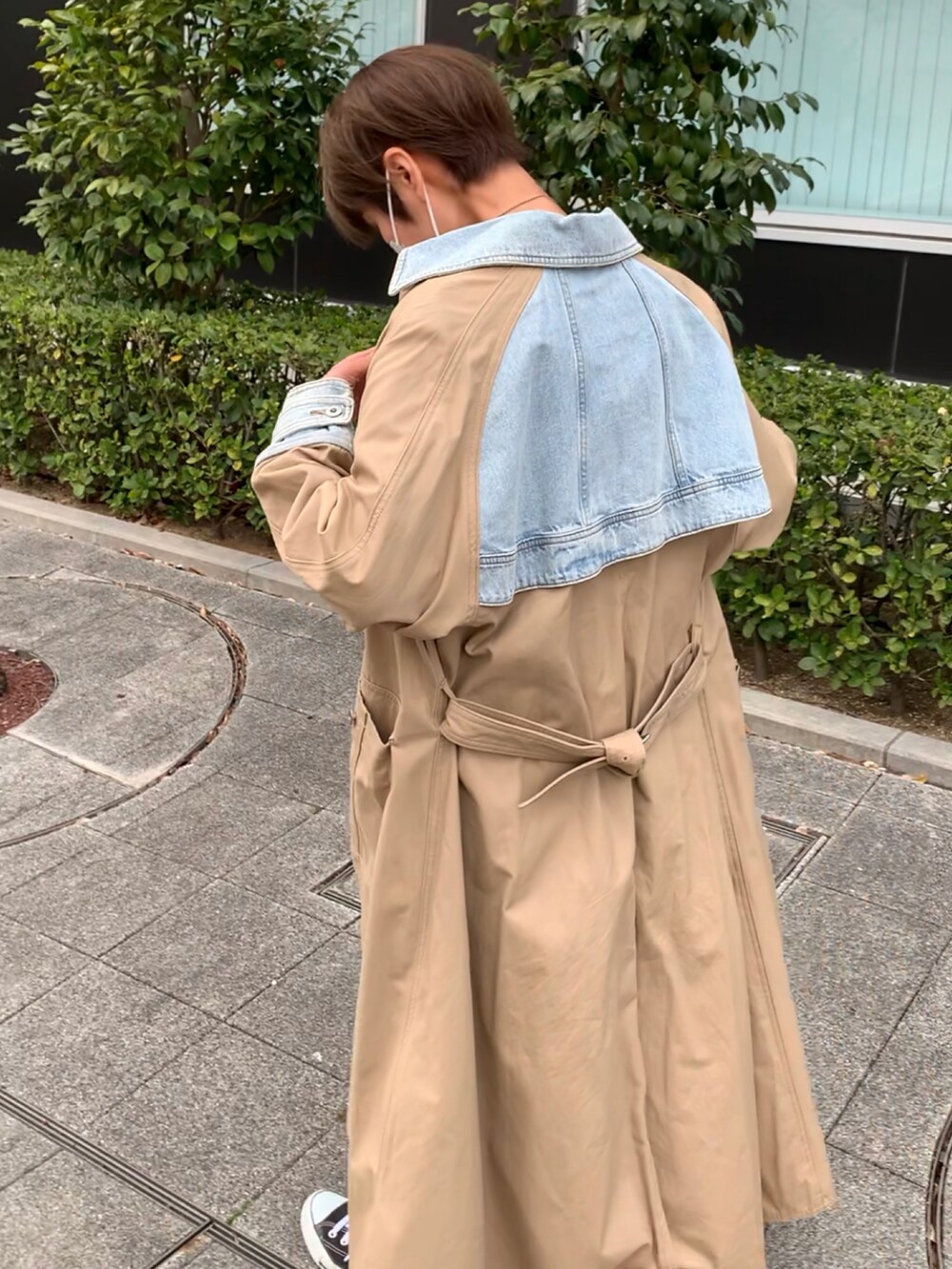 パープル系のTシャツ/カットソー、ベージュ系のトレンチコート、ブラック系のスニーカーを着用したレディースの春コーディネートの2枚目の写真