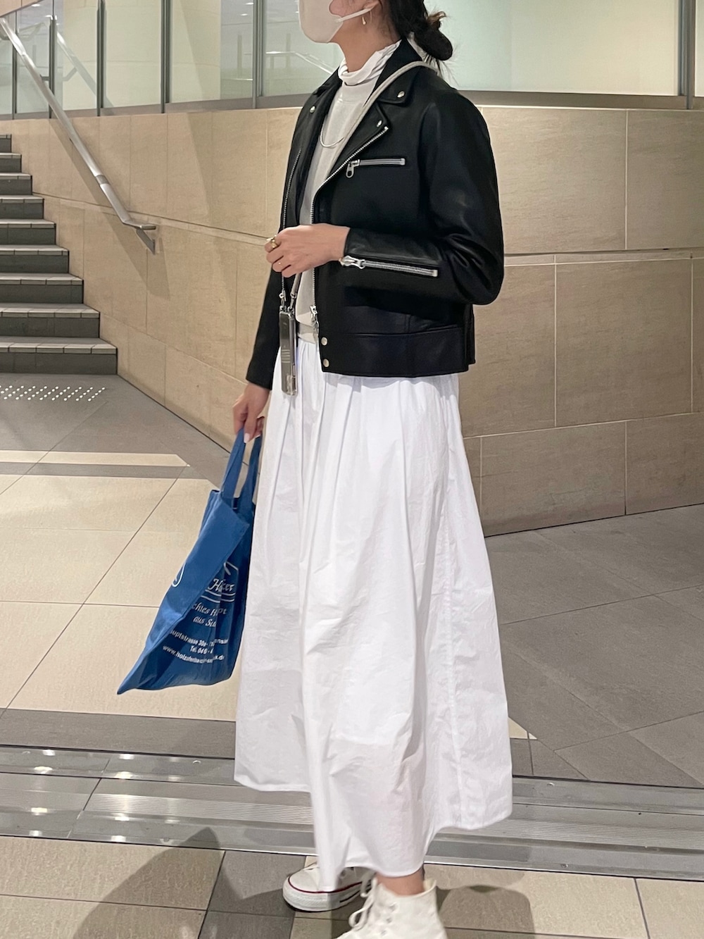 ブラック系のライダースジャケット、ホワイト系のスカートを着用したレディースの秋コーディネートの2枚目の写真