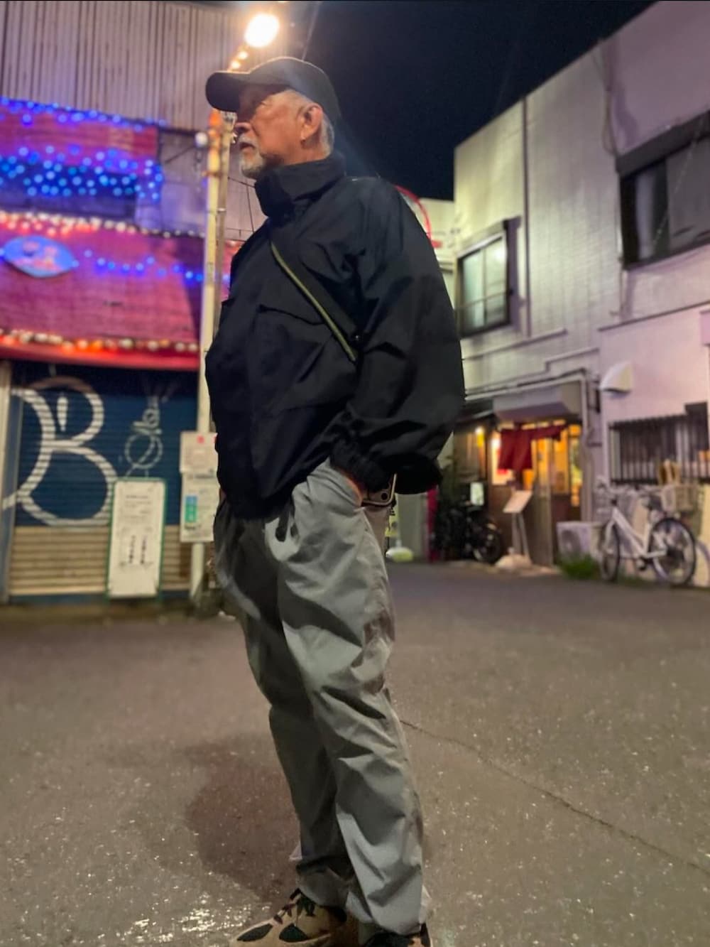 グレー系のその他パンツ、ブラック系のナイロンジャケット、ブラウン系のスニーカーを着用したメンズの秋コーディネートの2枚目の写真