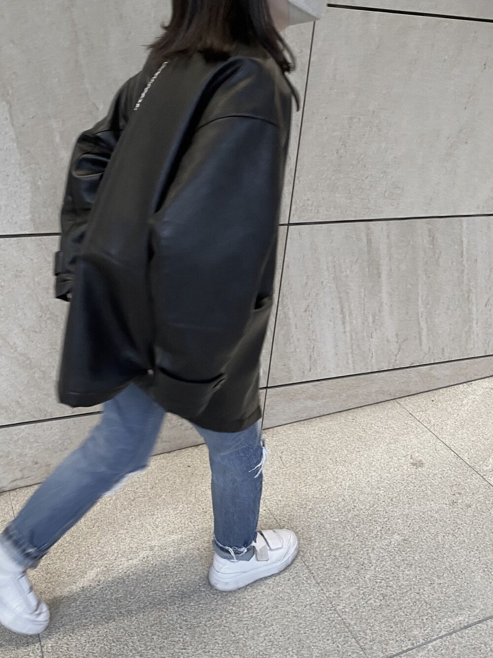 ブルー系のデニムパンツ、ホワイト系のスニーカー、ブラック系のその他アウターを着用したレディースの春コーディネートの3枚目の写真