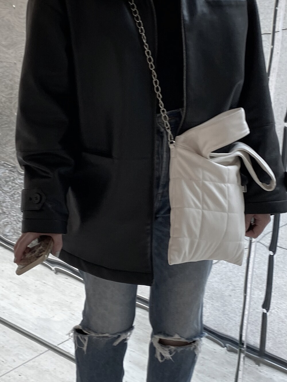 ブルー系のデニムパンツ、ホワイト系のスニーカー、ブラック系のその他アウターを着用したレディースの春コーディネートの2枚目の写真