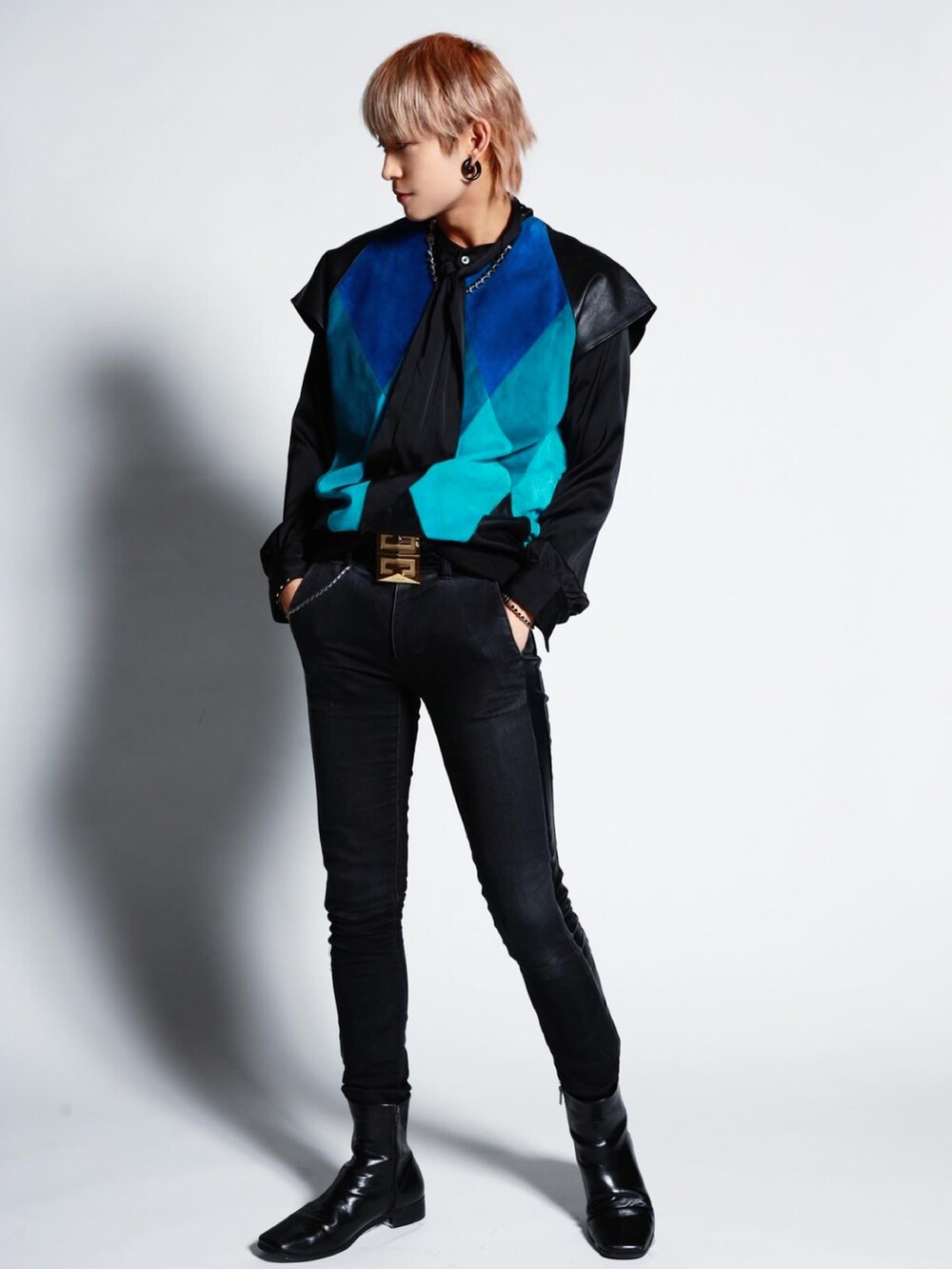 ブラック系のデニムパンツ、ブルー系のベスト、ゴールド系のベルトを着用したメンズの冬コーディネートの2枚目の写真