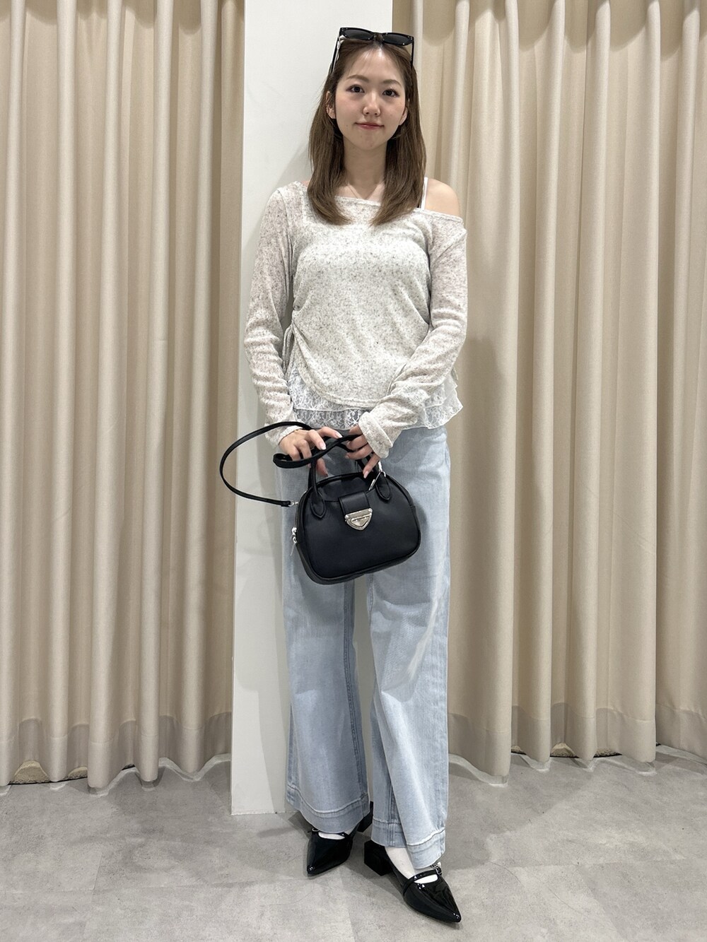 ブルー系のデニムパンツ、ブラック系のハンドバッグ、ホワイト系のTシャツ/カットソーを着用したレディースの春コーディネートの2枚目の写真