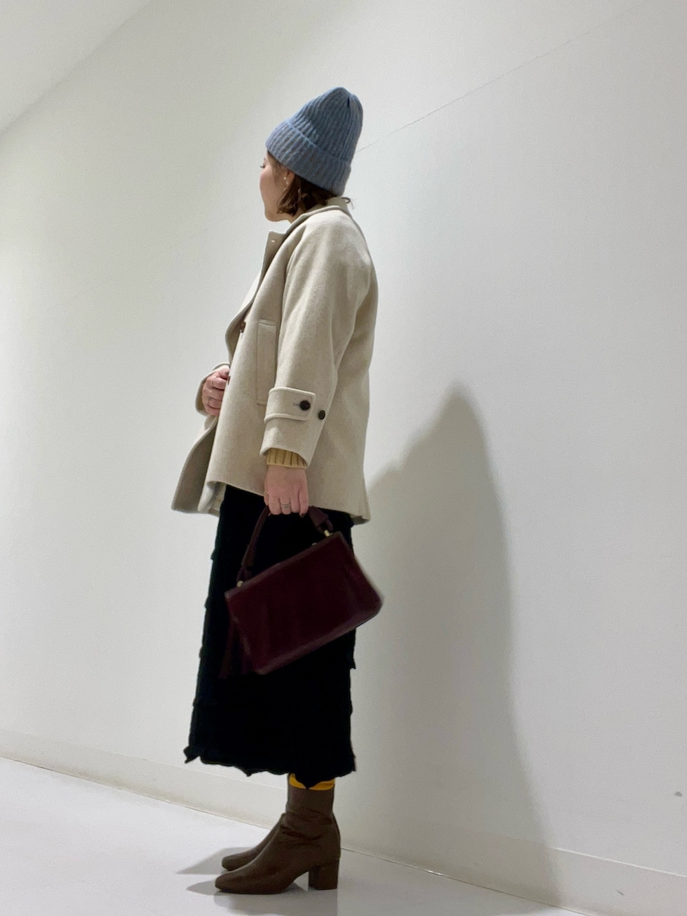 ベージュ系のピーコート、ベージュ系のトップス、ブラウン系のブーツを着用したレディースの冬コーディネートの2枚目の写真